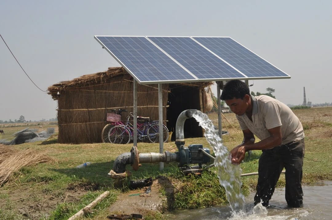 A farmer beside a solar-powered water pump in a field